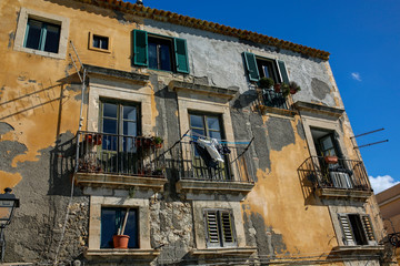 facade of typica italian rustic building with laundry and flowerpots