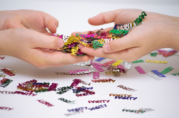 colorful, shiny confetti children hold in their hands