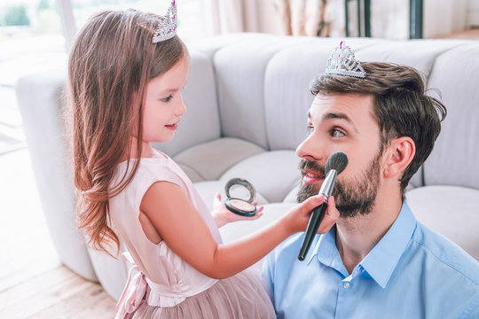caucasian father and daughter playing at home with make up brush
