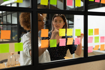 African american young female scrum master working with vietnamese colleague.