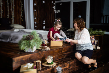 Obraz na płótnie Canvas Christmas, mom and daughter open gifts.