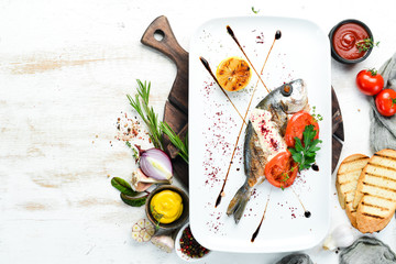 Dorado fish grilled with sauce and vegetables on a plate. Top view. Free copy space.