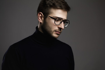 Young smart man wearing glasses and a folded polo neck