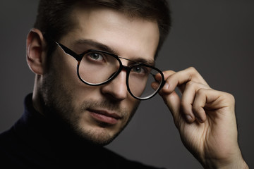 Young smart man wearing glasses and a folded polo neck