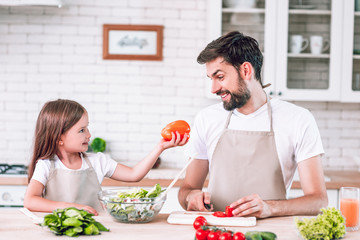 girl showing her father bell bell pepper on domestic kitchen