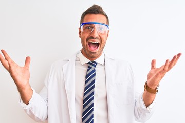 Young handsome scientist man wearing safety glasses over isolated background celebrating crazy and amazed for success with arms raised and open eyes screaming excited. Winner concept