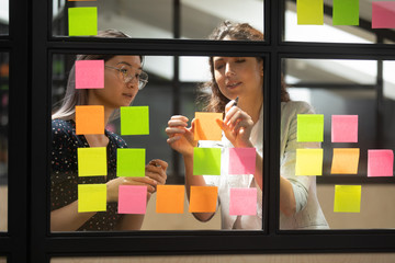 Two multiracial female partners planning business project.