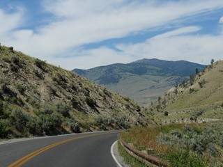 Naklejka premium Medium close up of a scenic winding road at Yellowstone National Park on a beautiful day near the Gardiner exit in Montana.