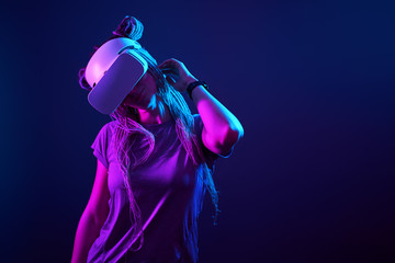 Woman is using virtual reality headset. Neon light studio portrait.