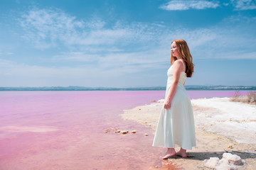 Fototapeta na wymiar Side view of cute teenager woman wearing summer clothes on pink lake