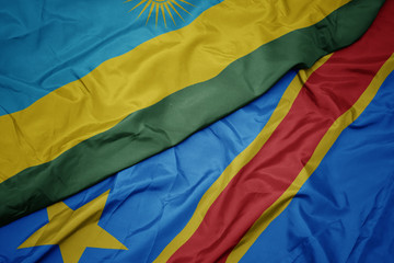 waving colorful flag of democratic republic of the congo and national flag of rwanda.