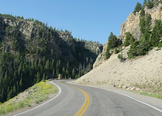 Winding road around cliffs and rocky mountains at the Grand Loop of Yellowstone National Park in Wyoming, USA.