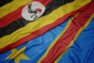waving colorful flag of democratic republic of the congo and national flag of uganda.