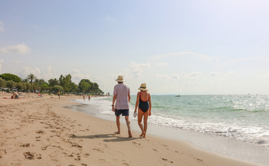 An older couple walking along the nice and sandy beach near a campsite in northern spain, at the costa brava