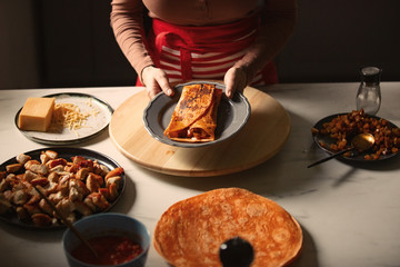 Woman cooking burrito with baked ingredients in a kitchen