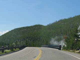 Beautiful views driving around the Yellowstone National Park in Wyoming, with steam rising from geysers by the road.