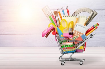 Stationery objects in mini supermarket cart on  background