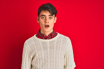 Fototapeta premium Teenager boy wearing a sweater standing over pink isolated background afraid and shocked with surprise expression, fear and excited face.