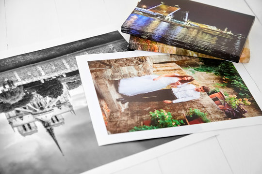 Photography canvas prints on white wooden background. Wedding and travel photos printed on glossy synthetic canvas
