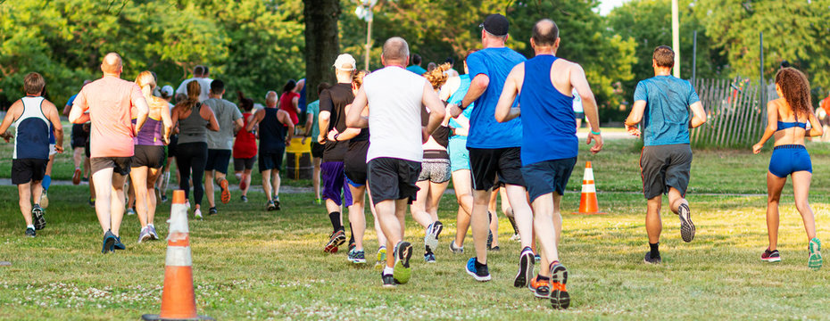 Horzontal View Of Runners Racing On Grass From Behind