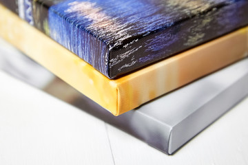 Photography canvas prints. Stack of colorful photos with gallery wrap on white wooden table....