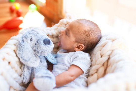 Adorable baby lying down over blanket on the floor at home. Newborn relaxing and resting comfortable with teddy bear