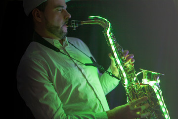 Saxofonista con gorra tocando saxofón en discoteca con luces led y fondo negro