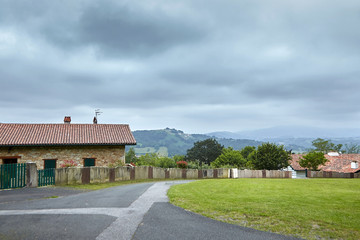 Fototapeta na wymiar Village in the foothills, countryside at overcast weather. Rural landscape, Basque country, Atlantic Pyrenees, France.