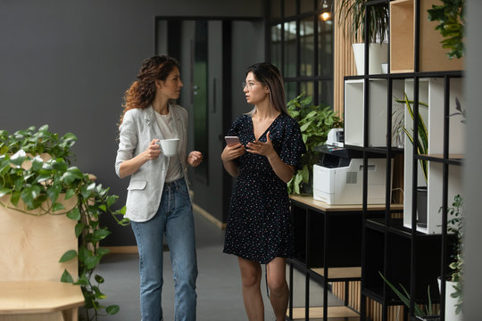 Multicultural female colleague discussing working issues during walk at office.