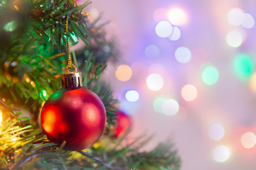 Christmas decoration. Hanging red balls on pine branches Christmas tree garland and ornaments over abstract bokeh background with copy space.
