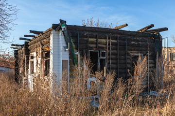 Fototapeta premium The ruins of a wooden house, damaged by a fire with protruding burnt beams of overlapping against the blue sky