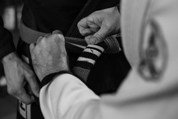 Promotion during brazilian jiu jitsu training. Close up, black and white photo of trainer's hand...