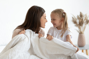 Preschool kid girl playing with happy young mommy in bedroom.