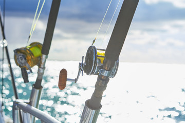 Trolling fishing boat rod and golden saltwater reel deep blue ocean sea wake. Dominican Republik Punta Cana Fishing boat.