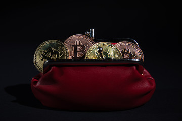 Gold metal Bitcoins in red leather wallet on black background