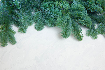 Christmas or New Year background: fir tree branches, glass balls, decoration and cones on a white plaster background