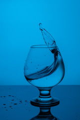 splash of water in a  blue glass with drops on glass