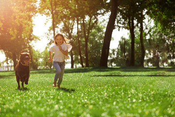 small girl and labrodor running in the park, full length shot