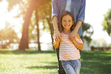 adorable girl standing with mother in the park and holding hands