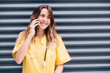 Chica hablando por teléfono durante su descanso en el trabajo de enfermera. Feliz y sonriente con su smartphone.