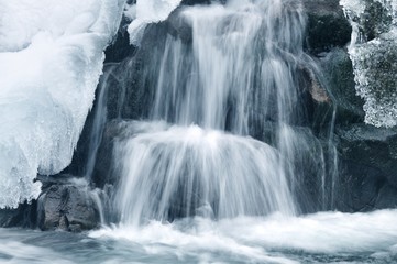 Beautiful snowy waterfall flowing in the mountains