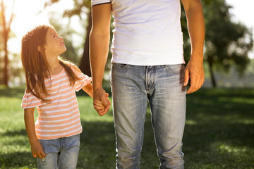 cute girl looking up at her father in the park, cropped shot