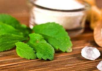 Stevia leaves with sugar in a glass bowl on a wooden background. Selective focus.