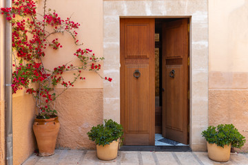 Fototapeta na wymiar Spanish house with door and flowers on street in beautiful Old Town of Alcudia. Balearic architecture.Majorca island. Spain