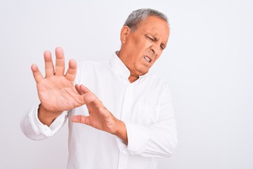 Senior grey-haired man wearing elegant shirt standing over isolated white background disgusted expression, displeased and fearful doing disgust face because aversion reaction. With hands raised.