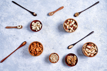 pecans, hazelnuts, almonds, pine nuts, Brazil nut, cashews in wooden bowls on blue background, top...