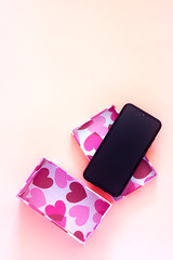 GIFT BOX WITH HEART DRAWINGS AND MOBILE PHONE ON PINK FUND. CHRISTMAS GIFT AND DAY OF SAN VALENTIN