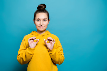 girl in a sweatshirt holds a broken cigarette and smiles