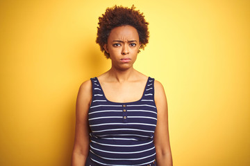 Beauitul african american woman wearing summer t-shirt over isolated yellow background skeptic and nervous, frowning upset because of problem. Negative person.