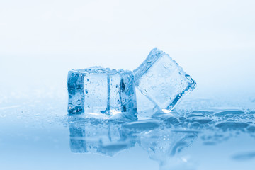 Naklejka na ściany i meble Ice two cubes square with drops water clean on blue background